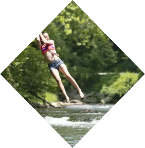 girl swinging on a rope swing above river