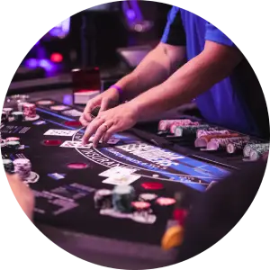 A close-up view of a casino table at Harrah's location with cards and chips spread out, with a dealer and players' hands engaged in a game.