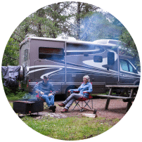 couple sitting around fire infront of RV