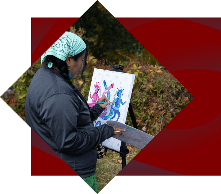 An artist painting colorful, whimsical figures on a canvas, set up on an easel outdoors, surrounded by nature. the artist is focused intently on her work.