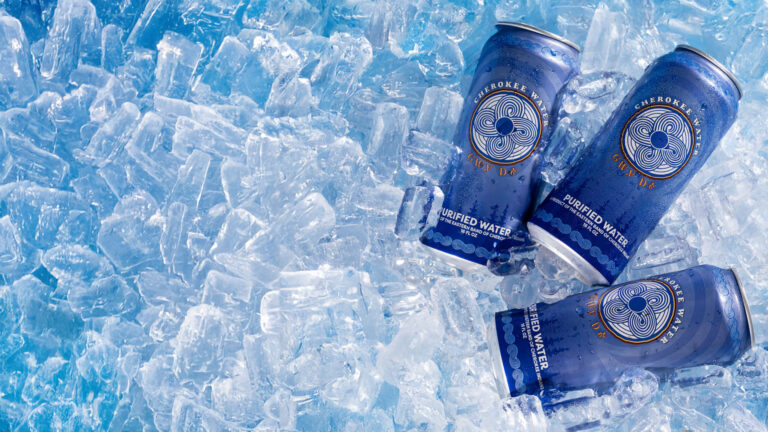 Three cans of Cherokee Canned Water sitting on top of ice.