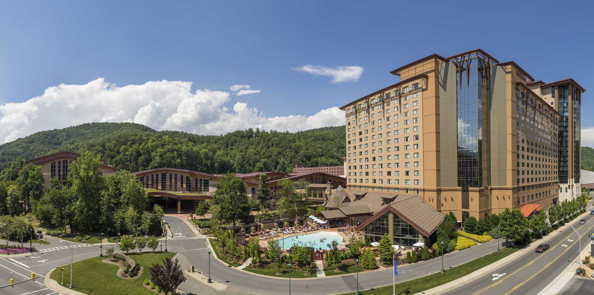 Outdoor view of Harrah’s Cherokee Resort with a large pool in the foreground and the hotel building in the background. 