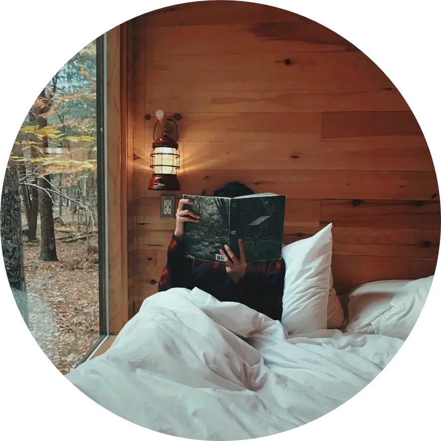 person sitting on bed in cabin reading