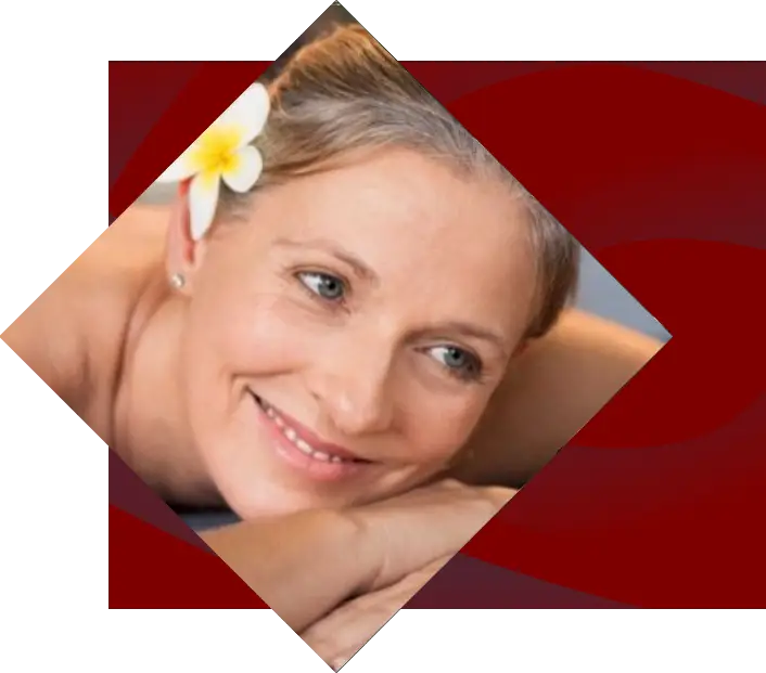 A smiling middle-aged woman with a flower in her hair, resting her head on her hand against a red swirling background at Harrah’s Cherokee.